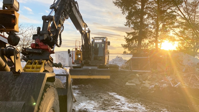Rivning av gammal sommarstuga på havstomt med grävmaskin och hjullastare